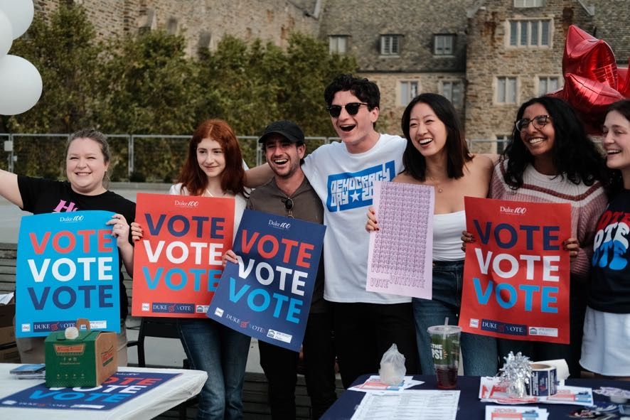 Laughing YPA members holding VOTE signs at a campus Democracy Day event
